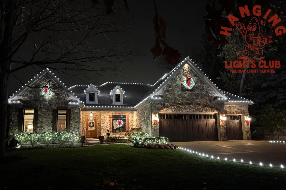 A beautifully lit house with white lights on the roofline and a lit driveway