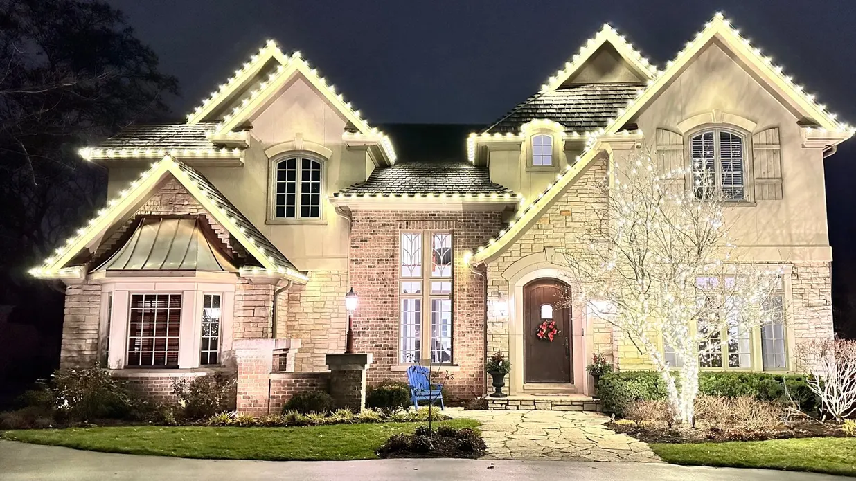 The same house at night, beautifully decorated with festive holiday lights
